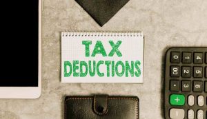 Foto con scritta Tax Deductions e calcolatrice, portafoglio e altri dispositivi