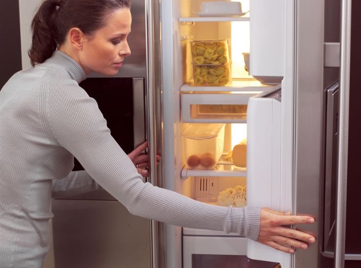 Donna cerca cibo all'interno del frigorifero