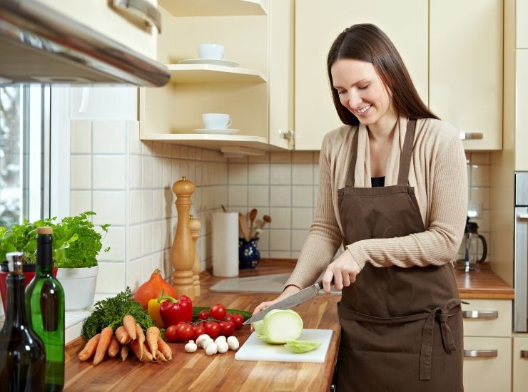 Donna che affetta le verdure sul tagliere di legno