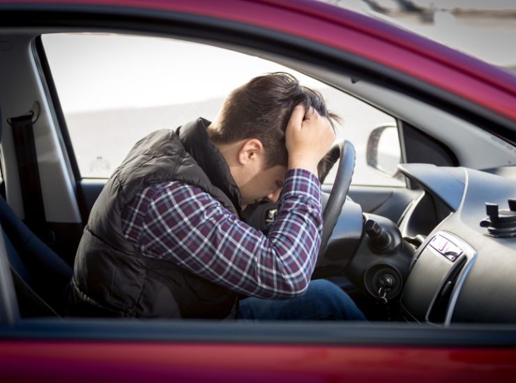 Ragazzo alla guida con testa sul volante