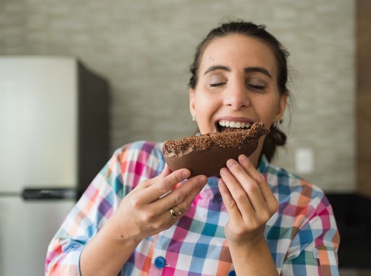 Ragazza con metà uovo di Pasqua al cioccolato in mano